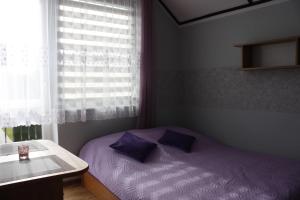 a small bedroom with a purple bed and a window at Ugeni ,apartament in Ostrowo