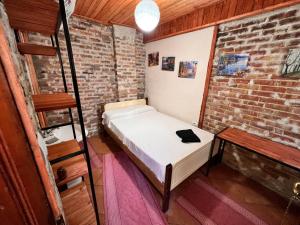 um pequeno quarto com uma cama e uma parede de tijolos em Rooms Nesti INSIDE OF CASTLE em Krujë