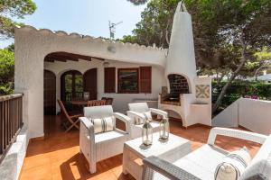 a patio with white chairs and a fireplace at Villa Menorca Ses Roques Vermelles by Mauter Villas in Cala Morell