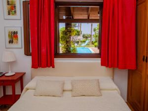 アラウリン・デ・ラ・トレにあるCubo's Villa Llanos de la Plataのベッドルーム1室(赤いカーテン、窓付きのベッド1台付)