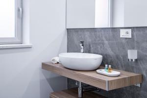 Appartamento Guglielmo في أوريستانو: حمام مع حوض أبيض على منضدة خشبية