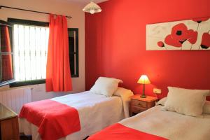 a red room with two beds and a window at Alojamiento Rural Las Maravillas in Cañada Catena