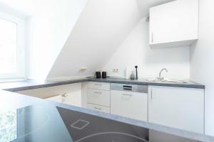 a kitchen with white cabinets and a sink at Hotel BUTZ in Scharbeutz