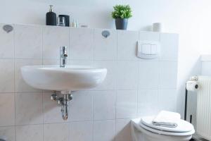 a white bathroom with a sink and a toilet at Hotel BUTZ in Scharbeutz