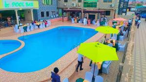 una piscina en un complejo con gente sentada bajo sombrillas en Hotel Green en Spintex