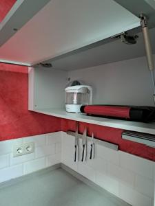 una cocina con armarios blancos y una pared roja en Piso familiar y con encanto, en Sevilla