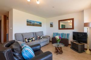 a living room with a couch and a tv at White Lodge Apartments in Mawgan Porth