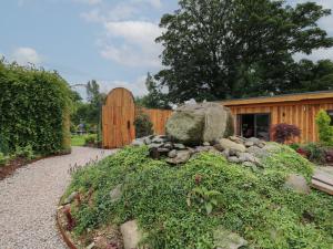 a garden with a rock and a wooden building at Fioled in Welshpool