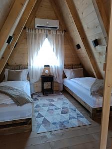 two beds in a attic room with a window at Stone Chalets - TERRA in Jajce