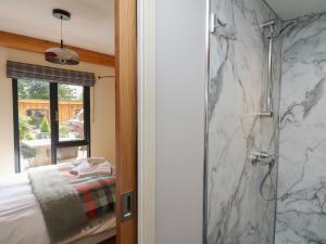 a bathroom with a shower and a bed and a window at Pansi in Welshpool