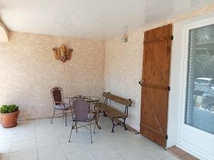 - une terrasse couverte avec 2 chaises, une table et une porte dans l'établissement la cigogne, à Céret