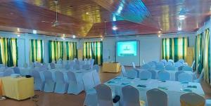 a room with white chairs and tables and a screen at Hotel Green in Spintex