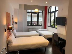 ein Hotelzimmer mit 3 Betten und einem Schreibtisch in der Unterkunft Calas De Liencres in Liencres