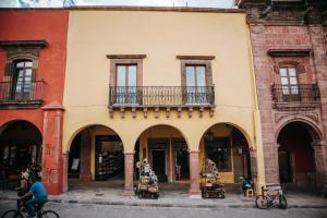ein Gebäude mit Bögen und Menschen, die vor ihm Fahrrad fahren in der Unterkunft Hotel Del Portal San Miguel de Allende in San Miguel de Allende