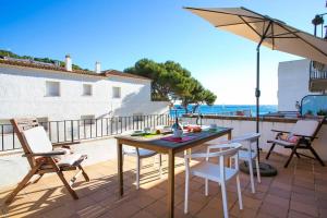 un patio con tavolo, sedie e ombrellone di Salitres Increíbles vistas a 50m de la playa a Tamariu
