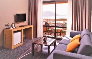 a living room with a couch and a television at Suhan Seaport 360 Hotel in Kuşadası