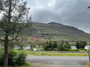 una montaña en la distancia con casas y una carretera en Árstígur 7, en Seyðisfjörður