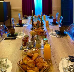 - une longue table avec des assiettes de viennoiseries et du jus d'orange dans l'établissement Le Henri IV, au Mans