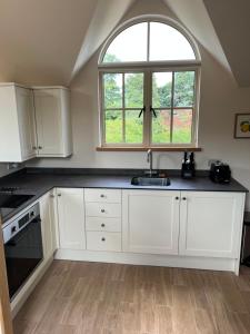 una cocina con armarios blancos y una ventana en The Loft, Steep, Petersfield in Collyers Estate part of The South Downs National Park., en Petersfield