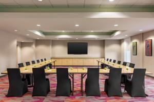 Home2 Suites by Hilton Lubbock في لوبوك: قاعة اجتماعات مع طاولات وكراسي وتلفزيون بشاشة مسطحة