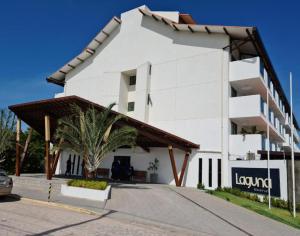 a white building with a palm tree in front of it at Flat 402 Laguna Beach - tipo Loft encantador, mobiliado e aconchegante in Porto De Galinhas