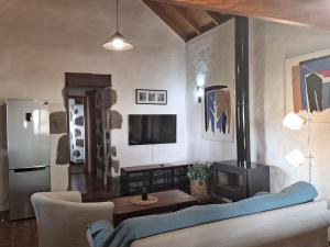 ein Wohnzimmer mit einem Sofa, einem TV und einem Herd in der Unterkunft CASA RURAL CON PISCINA PRIVADA El ROBLE in Moya