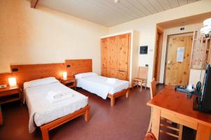 um quarto de hotel com duas camas e uma televisão em Pràcatinat Hotel & Restaurant em Fenestrelle