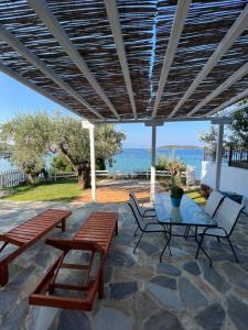 a patio with a table and benches and the ocean at Villas Nies in Soúrpi