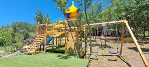 un parque infantil de madera con tobogán y columpios en TreeHouses Ljubač Glamping Robinson, en Ljubač