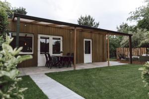 cobertizo de madera con mesa y sillas en un patio en Imagine Tiny House 325 op Camping GT te Balen, en Balen