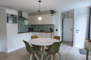 a kitchen with a white table and green chairs at Imagine Tiny House 325 op Camping GT te Balen in Balen
