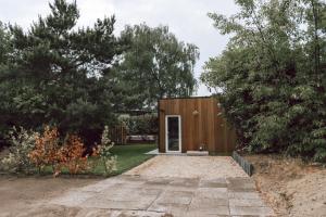 een houten huis met een deur in een tuin bij Imagine Tiny House 325 op Camping GT te Balen in Balen