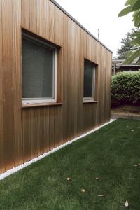 un edificio de madera con 2 ventanas y un patio en Imagine Tiny House 325 op Camping GT te Balen, en Balen