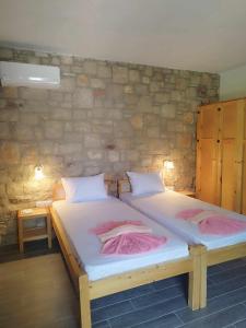 two twin beds in a room with a stone wall at Tropical Garden Prime Accommodation in Faliraki