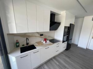 a kitchen with white cabinets and a black refrigerator at LA Lujuria in Ourense