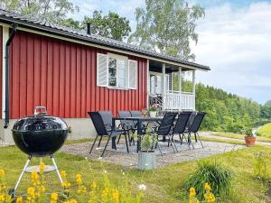a table and chairs in front of a red house at 6 person holiday home in MELLERUD-By Traum in Brålanda