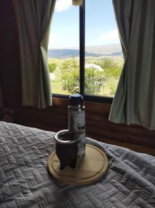 Una botella en una bandeja en una cama con ventana en Villa Nicolasa en Villa Yacanto