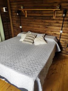 Cama en habitación con pared de madera en Villa Nicolasa en Villa Yacanto