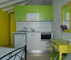 a kitchen with green cabinets and a yellow table at Studios Soula in Alonnisos