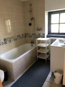 a bathroom with a tub and a sink at La Petite Maison Dans la Nature in Forges