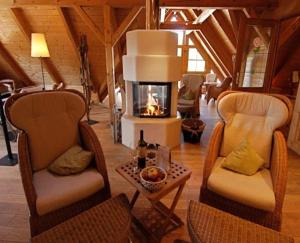 a living room with two chairs and a fireplace at Hotel Haferland in Wieck