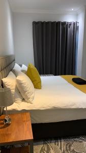 1 cama con almohadas amarillas y cortina negra en CALDESMO Private Apartment en Pretoria