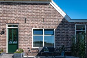 a brick house with a table and chairs in front of it at Boerderijkamer 't Keukentje in Wijhe