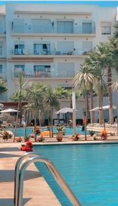 ein Pool mit Palmen und ein Gebäude in der Unterkunft Les jardins de Bouznika in Bouznika