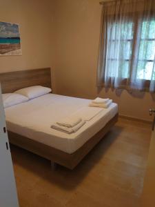 una camera da letto con un letto con lenzuola bianche e una finestra di Merida Apartments a Mola Kalyva