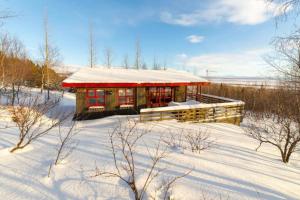 una cabaña en la nieve con techo rojo en Traditional Cottage with Jacuzzi and Lake View Laugarvatn, Árnessýsla, Islandia, en Laugarvatn