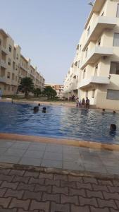 - une piscine en face d'un bâtiment avec des personnes dans l'établissement Appartement balnéaire Plage Sablette Mohammedia, à Pont Blondin
