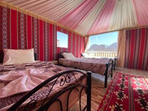 a bedroom with two beds in a room with red walls at Desert's Soul Wadi Rum in Disah