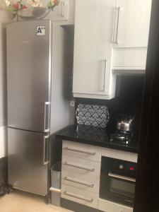a kitchen with a stainless steel refrigerator and white cabinets at L'appartement Bella Vista - Vue panoramique sur la Méditerranée WIFI in Cabo Negro