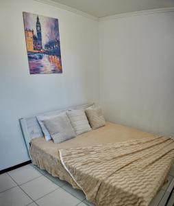 a bed in a bedroom with a painting on the wall at Vacation home Lubov in Kamianets-Podilskyi